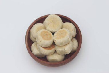 Beyaz arka planda izole edilmiş ahşap bir kasede servis edilen Bakpia 'nın yakın çekimi..