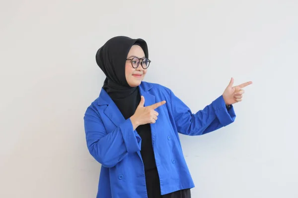 ヒジャーブ 青いブレザーを身に着けている美しい若いアジアのイスラム教徒の女性は自信を持って笑顔と白の背景に横向きに隔離された指している両手で幸せ 広告コンセプト — ストック写真