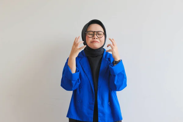 美しい若いアジア系イスラム教徒の女性 白い背景に隔離された悲しい表情で眼鏡と青のブレザーを身に着けています — ストック写真