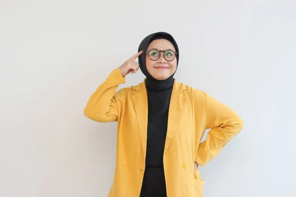 美しい若いアジア系イスラム教徒の女性は 眼鏡と黄色いブレザーを身に着けていることは白い背景に隔離されて考えている — ストック写真