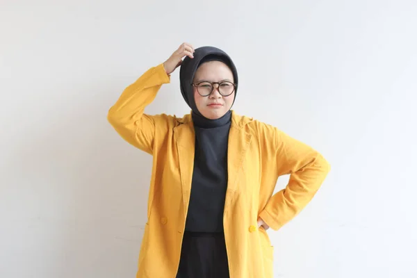 白い背景に隔離された頭を保持しながら ストレスジェスチャーを示す眼鏡と黄色のブレザーを身に着けている美しい若いアジアのイスラム教徒の女性 広告コンセプト — ストック写真