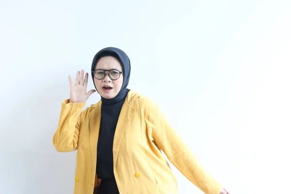 年轻美丽的亚洲穆斯林妇女 戴着眼镜和黄色的夹克 手握手势 听着因白色背景而被隔离的东西或人说话 — 图库照片