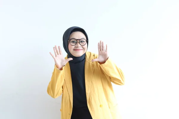 美丽的年轻的亚洲穆斯林妇女 戴着眼镜和黄色的夹克 露出手掌 同时笑着与外界隔绝的白色背景 广告概念 — 图库照片