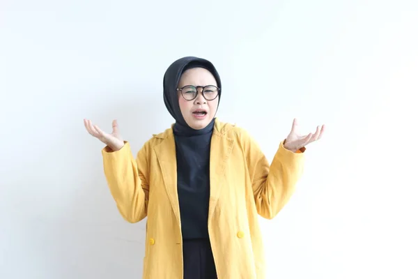 年轻美丽的亚洲穆斯林妇女 戴着眼镜 身穿黄色夹克 脸上困惑的表情与白色背景隔离 — 图库照片