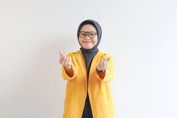 美しい若いアジアのイスラム教徒の女性 眼鏡をかけ 黄色のブレザーを身に着けています韓国の愛のサインをジェスチャーします — ストック写真