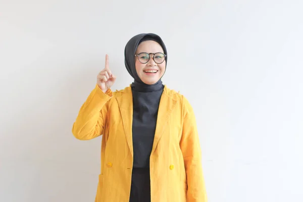 Красивая Молодая Азиатская Мусульманка Очках Жёлтом Пиджаке Думает Улыбаясь Изолированно — стоковое фото