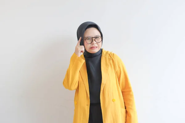 美しい若いアジア系イスラム教徒の女性は 眼鏡と黄色いブレザーを身に着けていることは白い背景に隔離されて考えている — ストック写真