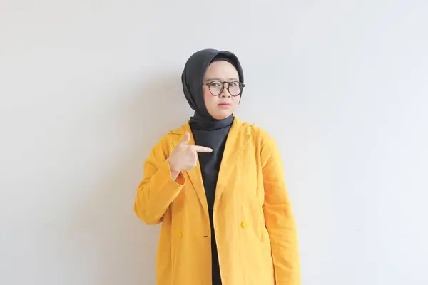 年轻美丽的亚洲穆斯林妇女 戴着眼镜 头戴头巾 头戴黄色夹克 手指向一边 白色背景隔离 广告理念 — 图库照片