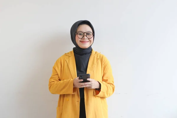 Красивая Молодая Азиатка Очках Хиджабе Жёлтом Пиджаке Держит Мобильный Телефон — стоковое фото