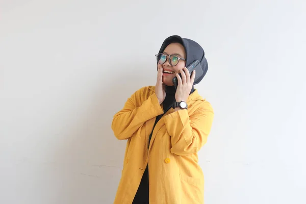 ヒジャーブの美しいアジア系女性の肖像画 眼鏡をかけ 黄色のブレザーを身に着けて電話をかけながら独立した白い背景を微笑む — ストック写真