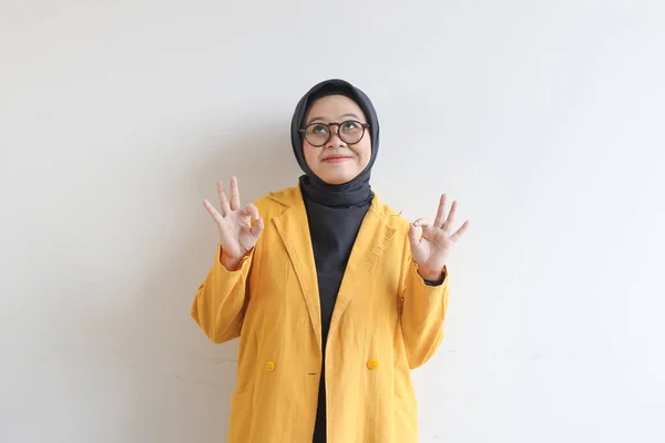 美しい若いアジアのイスラム教徒の女性 承認の手のジェスチャーで眼鏡と黄色のブレザーを身に着けているか Ok隔離された白い背景 — ストック写真