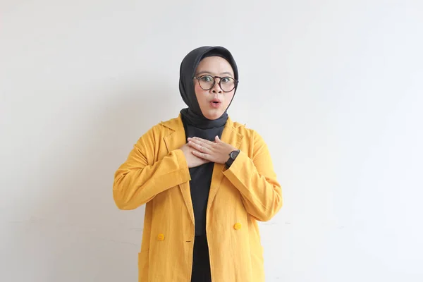 美しい若いアジア系イスラム教徒の女性 白い背景に隔離されたショックを受けた式と眼鏡と黄色のブレザーを身に着けています — ストック写真
