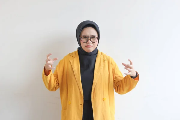 若いです美しいアジアのイスラム教徒の女性 白い背景に隔離された怒っている顔の表情と眼鏡と黄色のブレザーを身に着けています — ストック写真