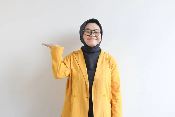 ガラス ヒジャーブ 黄色のブレザーを身に着けている美しい若いアジアのイスラム教徒の女性は自信を持って笑顔と手で幸せ白い背景に隔離された空のスペースを提示し 広告コンセプト — ストック写真