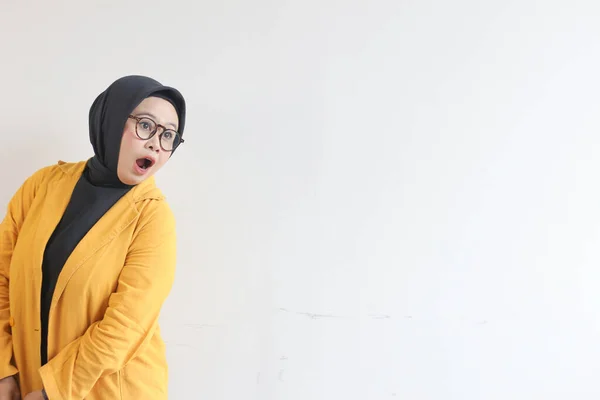 年轻美丽的亚洲穆斯林妇女 戴着眼镜和黄色的夹克 脸上带着震惊的表情 与白色背景隔离 — 图库照片