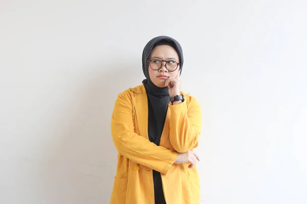 若い美しいアジアのイスラム教徒の女性は 白い背景に隔離された考えを見上げ黄色のブレザーを着ている 選択されたフォーカス — ストック写真