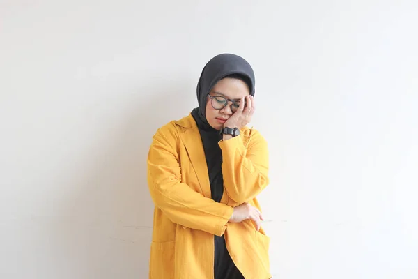 年轻美丽的亚洲穆斯林妇女 戴着眼镜 头戴黄色的夹克 手被白色的背景隔开 遮住了脸的一侧 — 图库照片