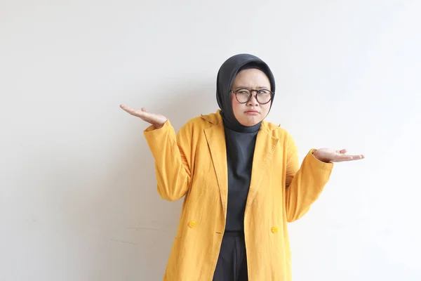 美しい若いアジア系イスラム教徒の女性 白い背景に隔離された混乱顔の表情を持つ眼鏡と黄色のブレザーを身に着けています — ストック写真
