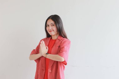Güzel Asyalı kadın portresi. Kırmızı elbise ve namaste jesti. Bu arada izole edilmiş beyaz arka plan gülümsüyor..
