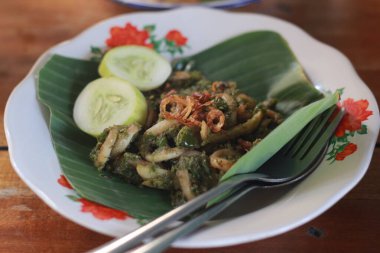 Bir porsiyon yeşil biberli kalamar, salatalık dilimleri ve bir tutam kızarmış soğan..