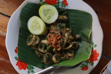 Bir porsiyon yeşil biberli kalamar, salatalık dilimleri ve bir tutam kızarmış soğan..