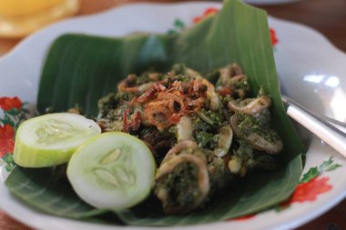 Bir porsiyon yeşil biberli kalamar, salatalık dilimleri ve bir tutam kızarmış soğan..