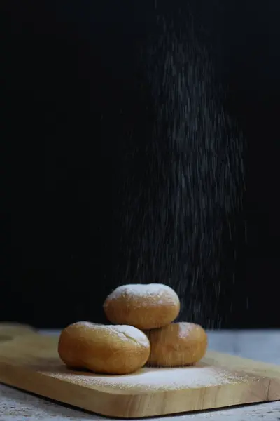Tahta bir tahtanın üzerinde toz şekerle tozlanmış üç altın esmer çörek. Mutfak lezzeti.!
