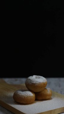 Üç lezzetli çöreğin görüntüsü, toz şekere bulanmış, sade ahşap bir tahtanın üzerine yerleştirilmiş. Cazip bir ikram.!