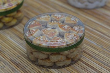 Susam tohumları serpiştirilmiş lezzetli Kastengel kurabiyeleriyle dolu bir kavanozun yakından görüntüsü. Bambu yüzeyindeki temiz bir kabın içinde düzgünce dizilmişler..