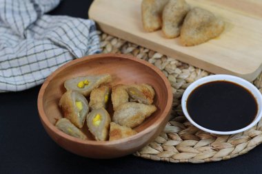 A close-up shot of pempek, a popular Indonesian fish cake, served with a rich dark sauce. The dish is presented beautifully in a wooden bowl. clipart