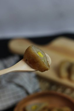 A close-up shot of a crispy Pempek on a wooden spoon.  Indonesian food. clipart