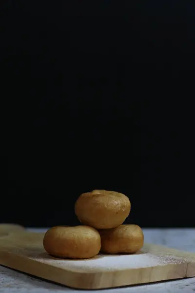 Tahta bir tahtanın üzerinde, koyu bir arka planda duran üç altın-kahverengi çörek. Ne hoş bir sürpriz.