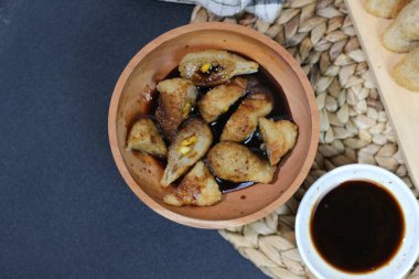 Popüler bir Endonezya atıştırmalığı olan Pempek 'in cazip bir üst görüntüsü, zengin siyah soslu ahşap bir kasede servis ediliyor..
