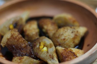 Geleneksel Endonezya balık keki olan Pempek 'in yakın plan bir resmi bir kasede servis ediliyor. Pempek altın rengi kahverengi ve çıtır çıtır görünüyor.