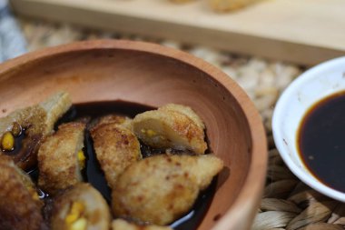 A bowl of Pempek Palembang, a famous Indonesian fishcake, served with a dark sweet and savory sauce. A delicious and crispy street food. clipart