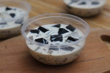 Plastik bardaktaki kremalı siyah jöleli tatlıya yakın çekim. Lezzetli ve ferahlatıcı.