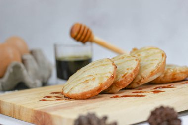 Indonesian kue lumpur, a delightful treat, drizzled with honey.  Served on a wooden board. clipart