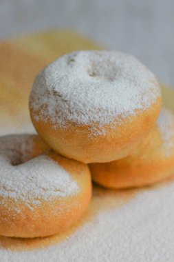 Cömertçe pudra şekerle kaplanmış üç altın esmer çörek bir yüzeye istiflenmiştir..