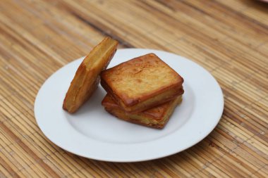 Tahta bir yüzey üzerinde, beyaz bir tabakta duran üç altın kahverengi kastengel kurabiyesi. Lezzetli bir ikram..