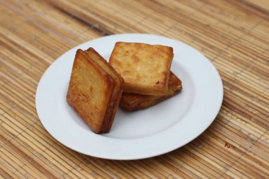 Beyaz bir tabakta üç tane çıtır altın sarısı Endonezya Kue kurabiyesi. Lezzetli bir yemek!