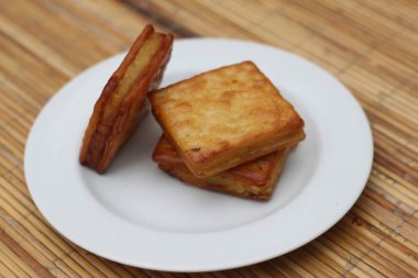 Beyaz bir tabağa düzgünce istiflenmiş üç altın sarısı kraker. Çekici ve lezzetli bir aperatif..