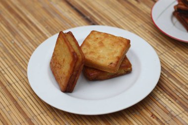 Geleneksel bir Endonezya hamur işi olan üç altın rengi Kue Sus, beyaz bir tabakta dinleniyor. Afiyet olsun.!