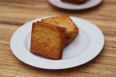 Beyaz bir tabağa istiflenmiş üç altın sarısı, çıtır kraker. Lezzetli bir atıştırmalık.