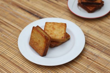 Sıcak ahşap bir yüzeye kurulmuş, beyaz bir tabakta duran üç altın-kahverengi kastengel kurabiyesi. Çıtır çıtır ve lezzetliler, atıştırmak için mükemmeller..