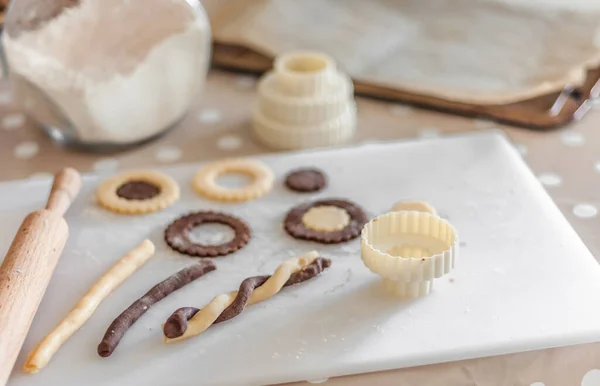 Cut from a short pastry and cooked cookies of different shapes on a cutting board, along with a can of flour, a baking sheet with baking paper and rolling pin.