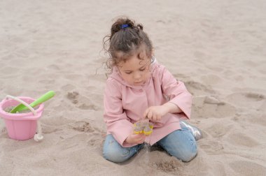 Genç kız sisli bir günde kumlarda oynuyor.