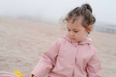 Genç kız sisli bir günde kumlarda oynuyor.