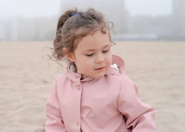 多愁善感的小女孩在雾蒙蒙的日子里在沙滩上玩耍 — 图库照片