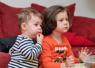 Cadılar Bayramı 'nda televizyon izlerken üzüm yiyen iki kardeş.