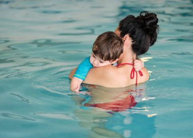 Havuzda annesi tarafından tutulan küçük bir çocuk.